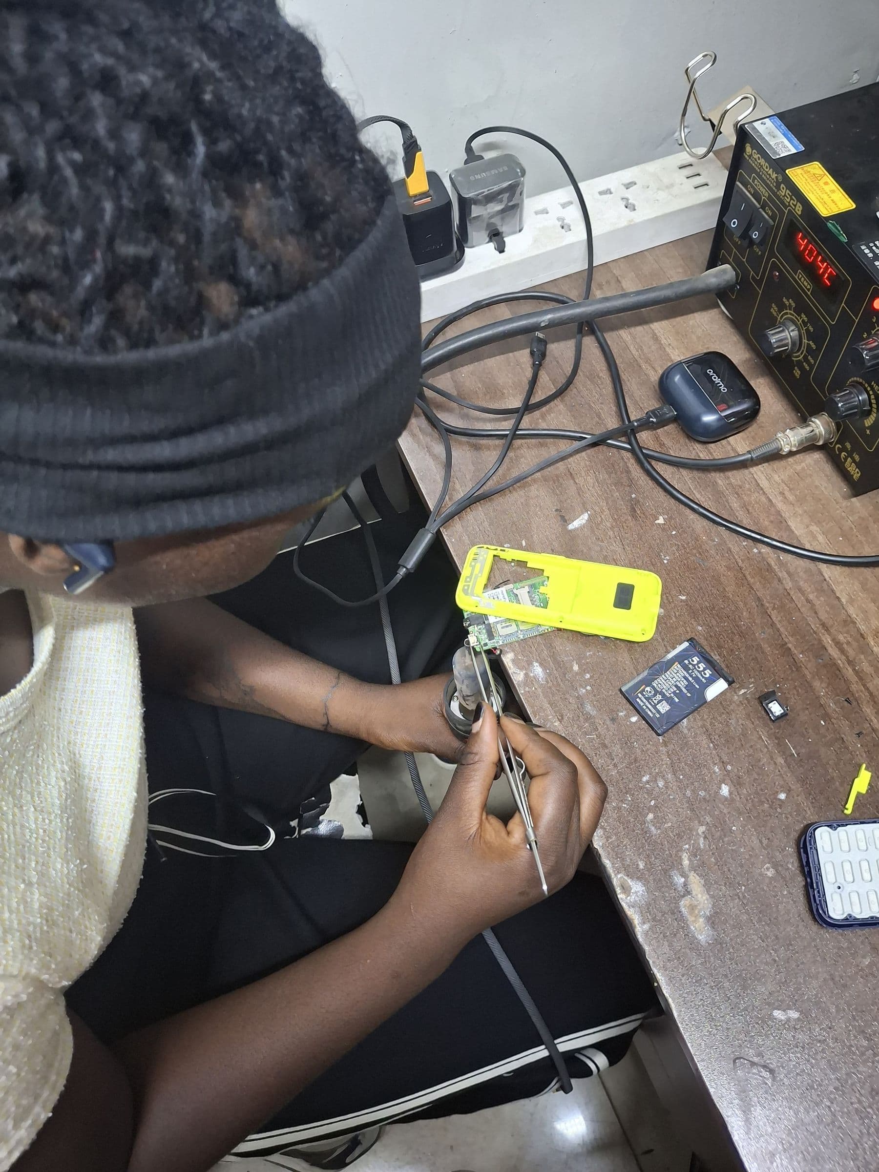 Shenitech technician at repair bench performing mobile phone repair with professional soldering station