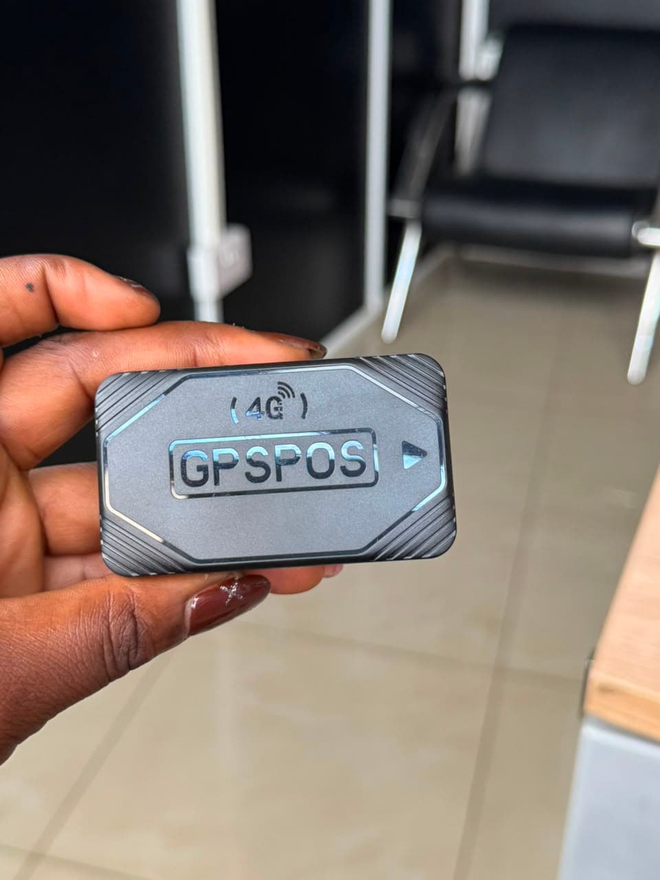 GPSPOS 4G vehicle tracker held in hand, showing the compact front housing supplied by Shenitech
